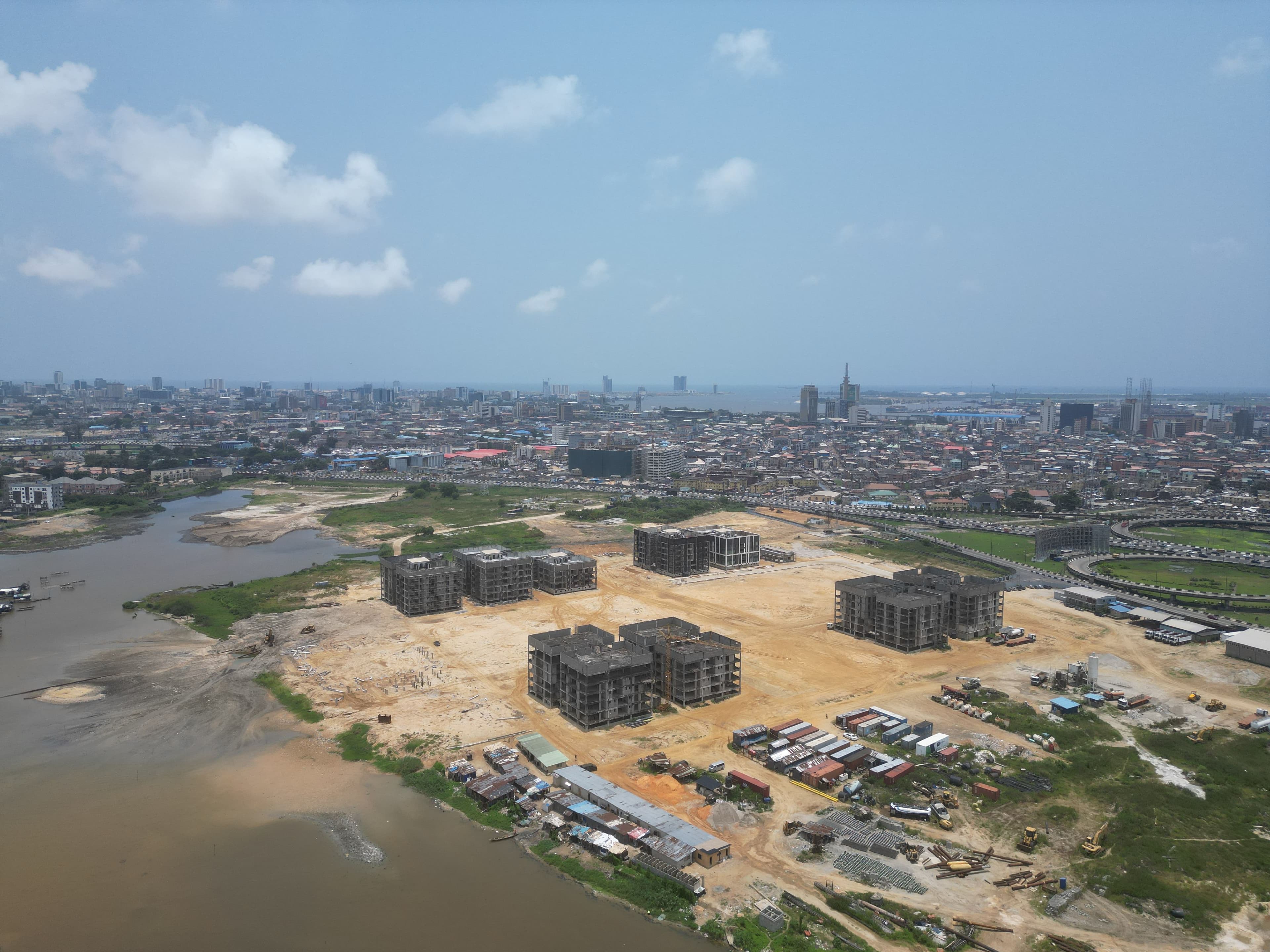 Aerial view of apartment blocks under construction beside the Lagos lagoon, with the city skyline behind